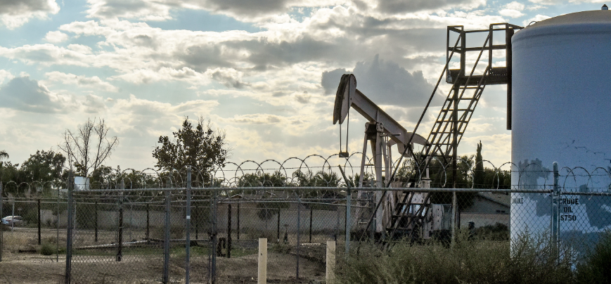 An oil drilling site with only a chain link fence separating it from the local community.