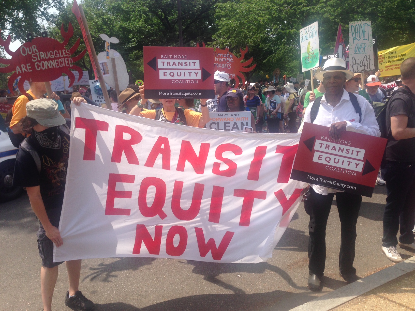 Supporters of the Baltimore Transit Equity Coalition hold a sign at the 2017 Peoples Climate March that reads "Transit Equity Now"