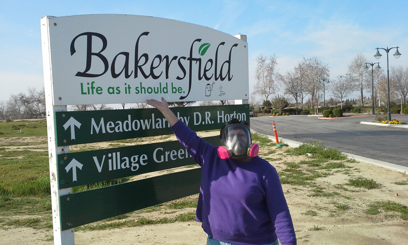 Rosanna in a respirator in front of a Bakersfield's sign